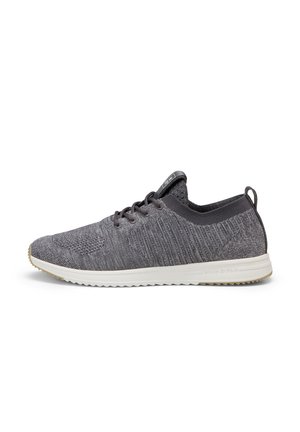 Baskets basses tricotées gris foncé avec col élastique, lacets noirs, semelle blanche et semelle extérieure texturée visible de côté.