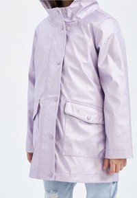 Lavendelfarbene, wasserdichte Jacke mit glänzender Optik, ausgestattet mit kleinen reflektierenden Punkten, einem hohen Kragen und Fronttaschen, die mit Druckknöpfen gesichert sind.