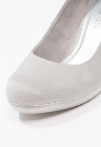 Gros plan sur une chaussure plate pour femme en daim gris clair avec un bout arrondi et une semelle intérieure rembourrée.