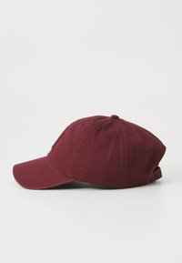 Bordo bejzbolska kapa s zakrivljenim vizirjem, dizajnom od šest panela i podesivim remenom. Sadrži suptilan logo i teksturiranu tkaninu.