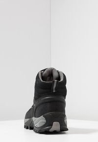Schwarzer Wanderstiefel mit einer strukturierten Oberseite und grauen Akzenten, gepolstertem Schaft und rutschfester Sohle für einen guten Halt. Die Rückansicht zeigt die Designdetails.