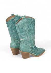 Botas de vaquero turquesas con superficie texturada y costuras decorativas. Presentan una punta afilada y un tacón cuadrado.