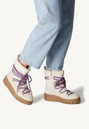 Bottines beige avec un col texturé doublé de fourrure, dotées de lacets violets et bleus colorés, d'une semelle en caoutchouc épaisse et d'une fermeture éclair sur le côté.