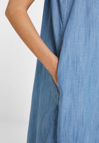 Jeansklänning i ljusblått med en mjuk struktur, med en sidofick som är integrerad i designen och visar en avslappnad passform.