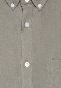 Chemise grise texturée à boutons blancs, col pointu et poche poitrine sur le côté droit.