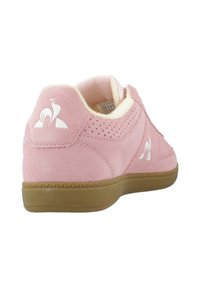 Baskets en suede rose avec une semelle en caoutchouc beige, présentant des panneaux perforés, un col rembourré et un logo blanc au talon.