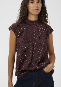 Blúzka s krátkym rukávom bordovej farby s vysokým golierom a záhybmi, s bodkovaným vzorom v svetloružovej farbe. Hladká látka, voľný strih.