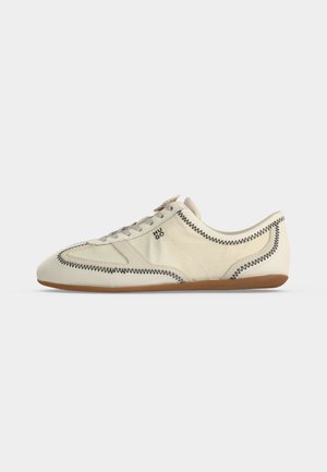 Λευκό sneaker χαμηλού τύπου με μαύρη ζιγκ-ζαγκ ραφή, γκρι κορδόνια, λαστιχένια σόλα και μικρό λογότυπο "HUGO" στο πλάι.