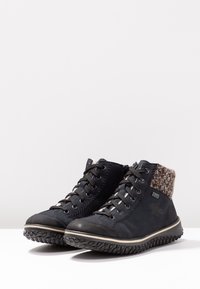 Chaussures montantes noires en daim, col en maille texturée, design à lacets et semelle en caoutchouc robuste avec une ligne d'accent blanche.