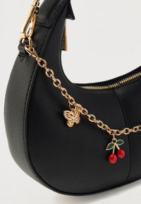 Sac en cuir noir de forme arrondie, orné d'une chaîne dorée, d'un charme en forme de papillon et d'un accent cerise. Dispose d'une fermeture éclair.