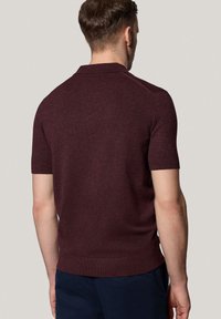 Burgundowa koszulka polo z krótkim rękawem o dopasowanym fasonie, z fakturowanej dzianiny, płaskim kołnierzykiem oraz prążkowanymi mankietami i dołem.