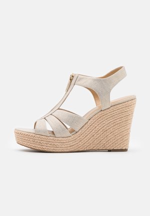 Sandalia cuña beige con parte superior de tela, con múltiples correas y cremallera lateral. La suela tejida tiene un diseño texturizado trenzado.