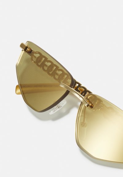 Gafas de sol en tono dorado con un marco geométrico. Lentes con tinte amarillo, detalle de cadena integrada y almohadillas nasales ajustables para mayor comodidad.