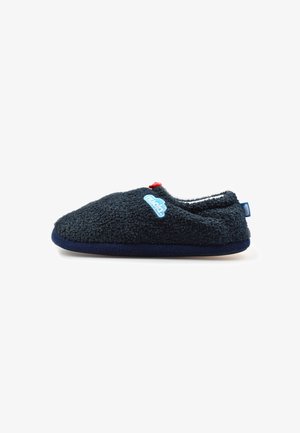 Una única zapatilla peluda azul oscuro con un botón rojo en la parte superior y una etiqueta de marca azul claro en el lateral sobre fondo blanco.