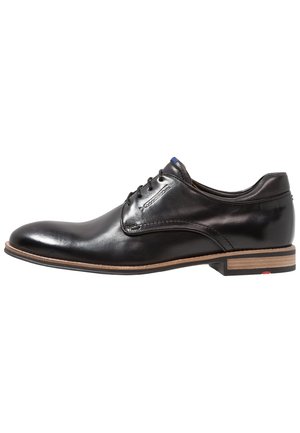 Chaussure habillée pour homme en cuir noir poli avec un design à lacets et une semelle beige avec un petit talon, vue de côté sur fond blanc.