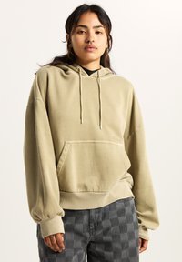 Khaki bluza z kapturem, z przednią kieszenią, sznurkiem do regulacji kaptura i ribbed mankietami. Miękka tkanina, luźny krój i minimalny detal z logo. Połączona z spodniami w kratę.