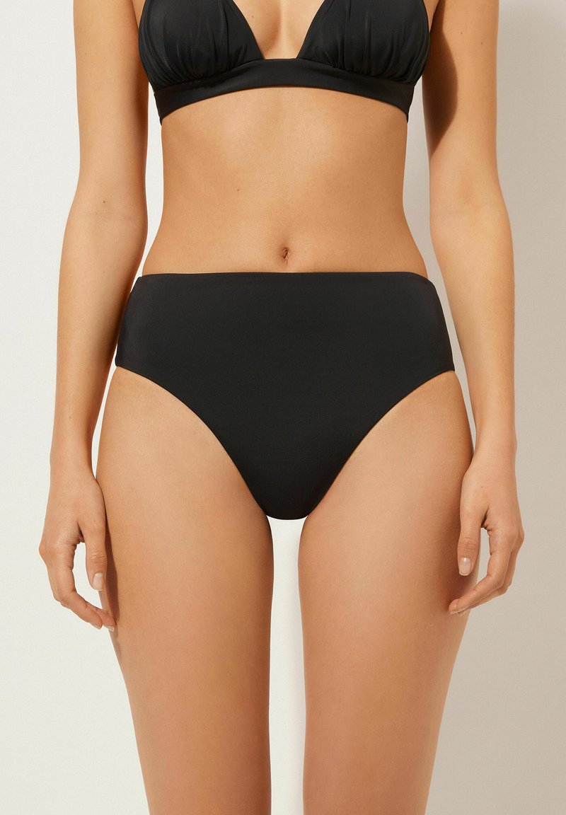 Hochgeschnittene schwarze Bikinihose aus glattem Stoff, mit einem schlichten Design und geschwungenen Beinausschnitten für eine bequeme Passform.