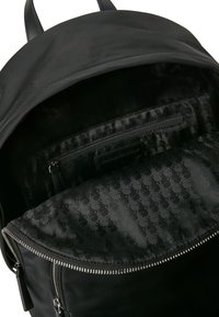 Fekete nylon hátizsák sima felülettel, cipzáras záródással és szövet béléssel, mely diszkrét mintázatot tartalmaz. Belső zsebében cipzáras részlettel.