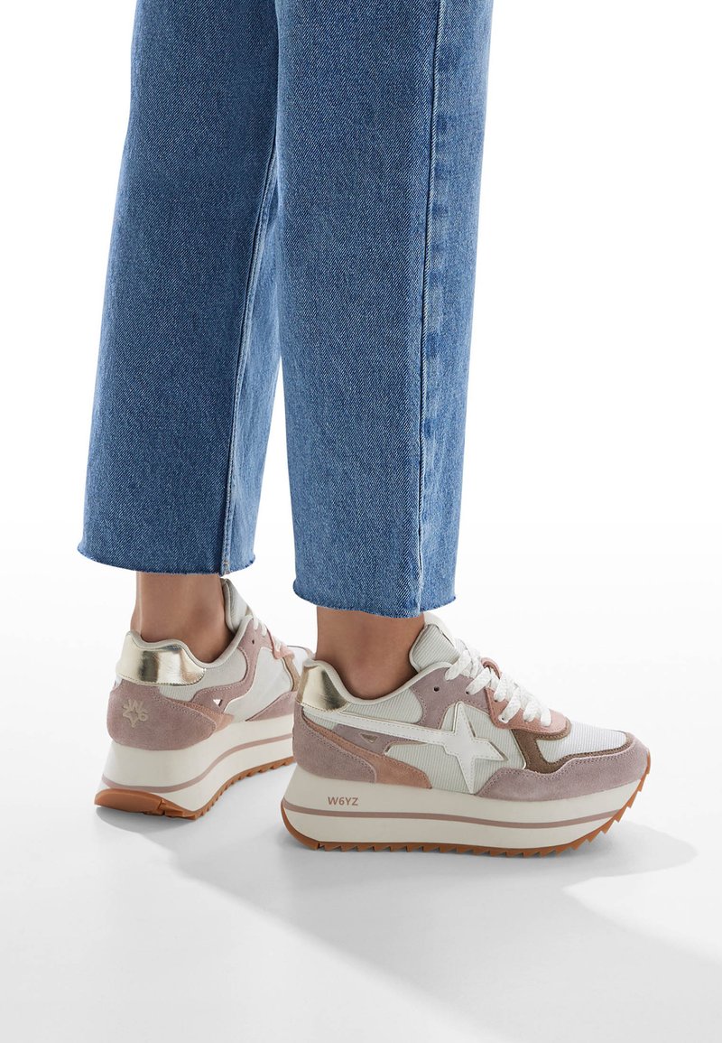 White and pink sneakers with a textured upper, suede accents, and a thick white outsole. Feature a side star design and laces.