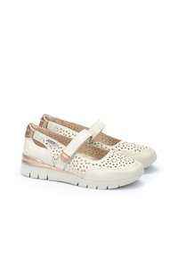 Scarpe color crema con tomaia in pelle forata, fascia regolabile e dettagli in oro metallico. Suola bianca spessa per un maggiore comfort.