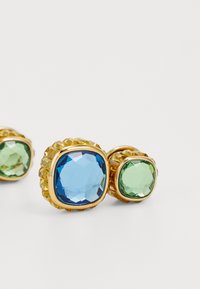Boucles d'oreilles dorées avec de grandes pierres facettées bleues et vertes, de forme ronde, ornées de sertissages décoratifs et de bords complexes.