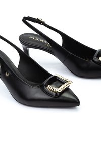 Zapatos de tacón de piel negra con punta afilada y detalle de hebilla dorada, con un tacón de altura media. Diseño minimalista.
