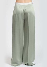 Pantaloni a palazzo verde chiaro realizzati in tessuto liscio e morbido. Presentano una vita alta e sottili pieghe in un design ampio e fluido.