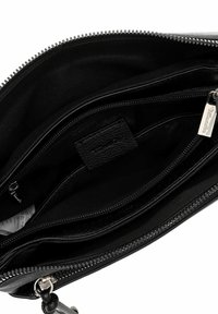 Black leather handbag interior featuring multiple compartments, smooth textures, and silver zipper hardware. Label visible on fabric lining.