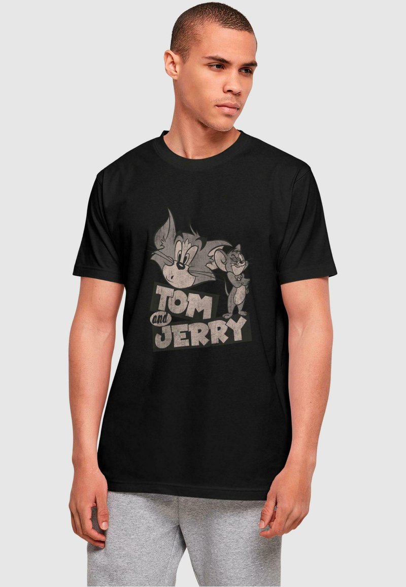 Black cotton t-shirt featuring a vintage print of cartoon characters Tom and Jerry in gray tones, with bold text reading "Tom and Jerry."