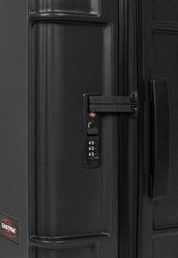 Černý tvrdý kufr s texturovaným povrchem, dvoucestnými zipy a kombinovaným zámkem. Na boku se nachází logo Eastpak.