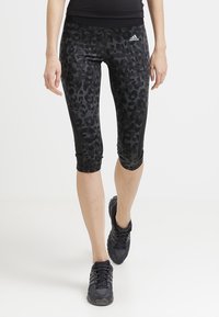 Leggings capri in stampa leopardata nera e grigia realizzati in tessuto elastico, caratterizzati da una texture liscia e una vita elastica.