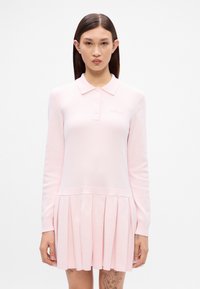 Ružová dlhá šaty s polo golierom, s plisovanou sukňou, hladkou textúrou a jemne vyšitým logom na hrudi.