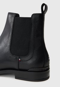 Botín Chelsea de cuero negro con panel lateral elástico, tirador en el talón, pequeño logotipo de tela y suela apilada.