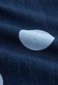 Sötétkék farmer anyag világoskék körkörös mintával. A textúra sima, jól látható szövésű, és enyhe árnyalateltérések figyelhetők meg.