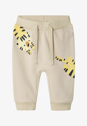 Pantalones cortos de algodón beige con cintura elástica, que presentan un estampado de tigre amarillo en la pierna izquierda y rayas negras en contraste. Puños acanalados.