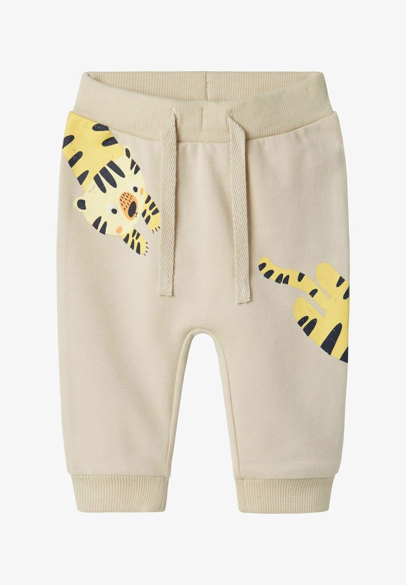 Beige cotton shorts with elastic waistband, featuring a yellow tiger print on the left leg and contrasting black stripes. Ribbed cuffs.