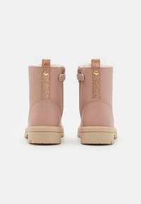 Botas de tobillo de cuero rosa con forro de piel, tirador trasero brillante en forma de corazón, con suela beige gruesa y cremallera lateral.