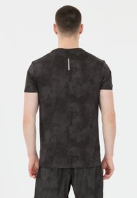 Mustat lyhythihaiset t-paidat, joissa on teksturoitu, tumma maastokuviot, takana heijastava pystysuora nauhaviimeistely.