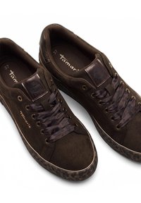 Pair of dark brown suede sneakers with satin laces, metal eyelets, and patterned rubber soles, branded with "Tamaris" on the sides and insoles.