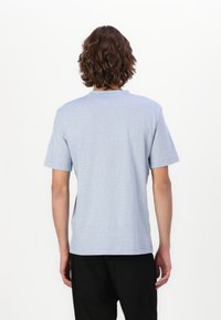 Světle modré tričko s krátkým rukávem a kulatým výstřihem, vyrobené z měkké tkaniny s jemnou texturou pruhů. Čistý, minimalistický design.