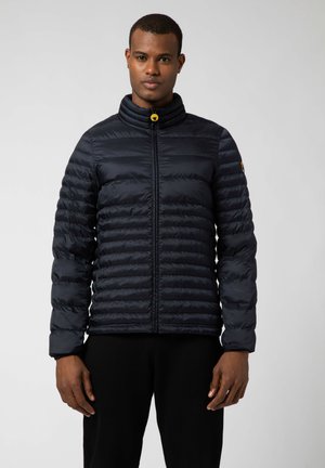 Giacca a vento blu navy con colletto alto, strisce orizzontali, zip completa e un tirazip giallo. Il tessuto appare liscio e leggero.