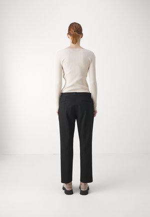 Cream ribbed long-sleeve top and black tailored pants. The top has a wide neckline; the pants feature a slim fit with back pockets. Black shoes.