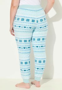 Světlé modré pyžamové kalhoty z měkké, strukturované látky. Mají vzor sněhových vloček a srdcí ve tmavě modrých odstínech. Na koncích s nápletem.