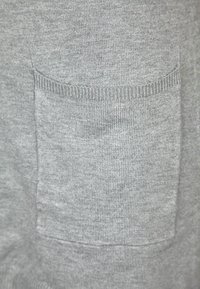 Grå sweatshirt tyg med en strukturerad yta, med en framträdande ficka framtill och ribbad detaljering längs kanterna.