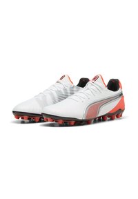 Botas de fútbol blancas con acentos rojos, una parte superior texturizada y un interior negro. Presentan una franja plateada a lo largo del costado y tacos rojos moldeados.