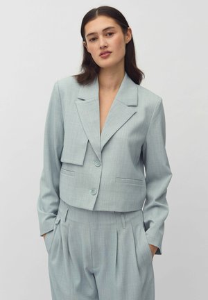 Blazer corto azzurro chiaro realizzato in tessuto testurizzato, con colletto a lancia, chiusura con bottoni e tasche laterali, abbinato a pantaloni plissettati.
