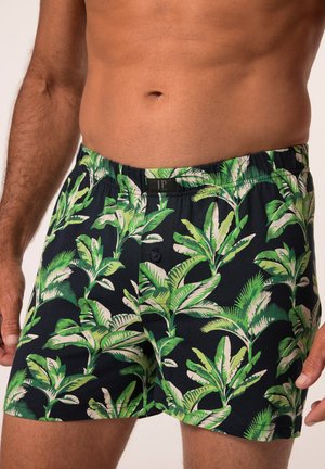 Schwarze Boxershorts mit einem lebendigen grünen Blattmuster. Aus Baumwolle gefertigt, mit einem elastischen Bund, Knopfverschluss und kontrastierenden weißen Akzenten.