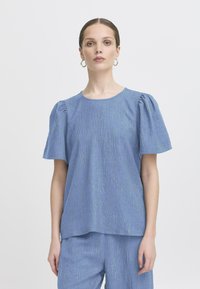 Bluza scurtă cu mâneci scurte, guler rotund, dintr-un material texturat, cu linii verticale subtile. Mânicile ușor bufante adaugă dimensiune.