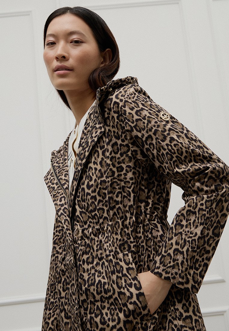 Veste en imprimé léopard avec capuche, fermeture éclair à l'avant et poches latérales. Fabriquée en tissu texturé, elle a une taille cintrée et des manches longues.
