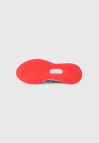 Semelle de chaussure de sport en caoutchouc rouge vif, présentant un motif de bande de roulement texturé avec une découpe centrale. Accents lisses en violet visibles.